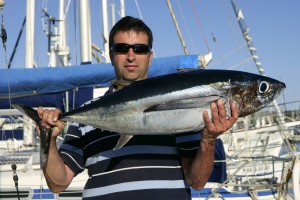 Big game fisherman with saltwater tuna catch in his hands
