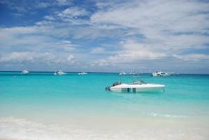Boats anchored off on clean blue water.